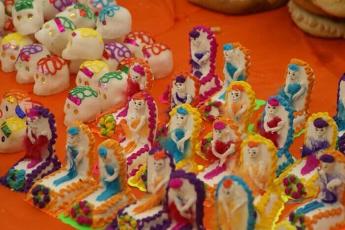 Tradiční bílé a zdobené calaveritas de azúcar k Día de los Muertos v Mexiku na oranžovém ubuse 