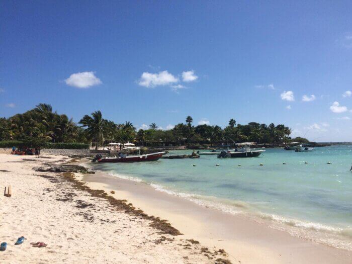 Pláž v Akumalu na Riviéře Maya s bílým pískem, palmami, čluny a tyrkysovým mořem