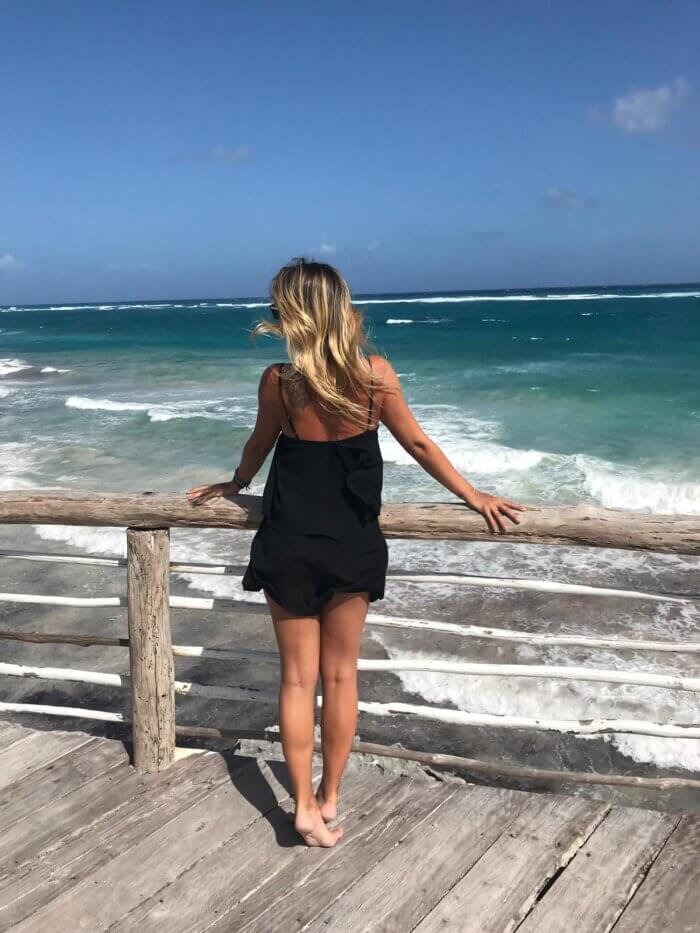 Postava ženy pozorující tyrkyrové karibské moře v Tulum