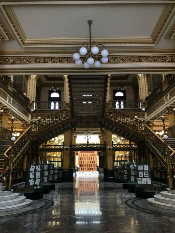Co dělat v Mexico City? Interiér Palacio Postal v Mexico City s monumentálním schodištěm a zlatými detaily.