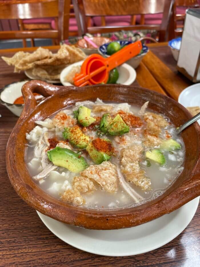 radiční mexická polévka pozole s bílou kukuřicí, masem, ředkvičkami, salátem a limetkou.