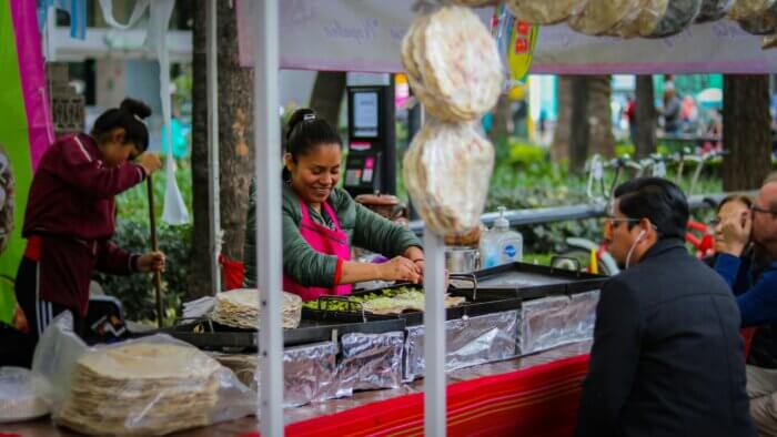 Pouliční prodavačka připravující tacos na trhu v Mexico City - typický street food v Mexiku. 