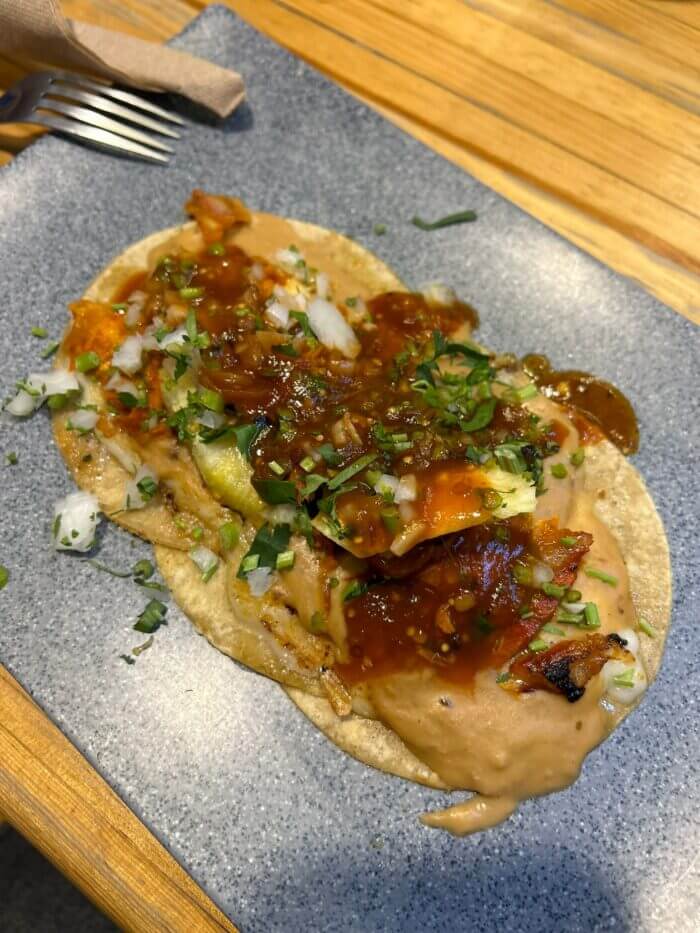 Tacos al pastor z restaurace El Tizoncito s ananasem a cibulí.