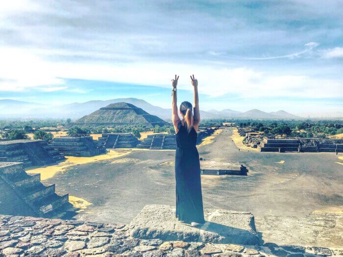 Jednodenní výlet z Mexico City - Osoba stojící na vrcholu Pyramidy Měsíce v Teotihuacánu s výhledem na monumentální Pyramidu Slunce v Mexiku.