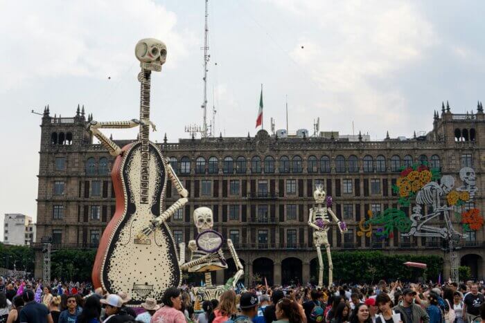 Zócalo v Mexico City plné lidí a velkých figurín Catrinas během oslav Día de Muertos.