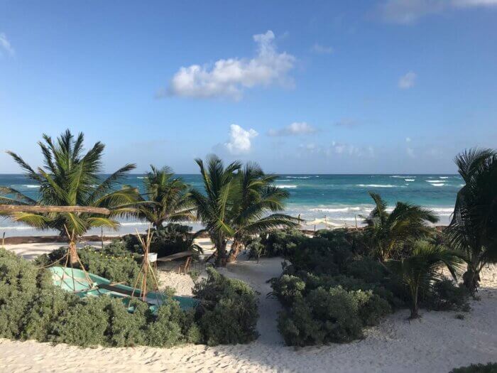 Pláž s bílým pískema tyrkysovým mořem a palmami v Tulum zona hotelera