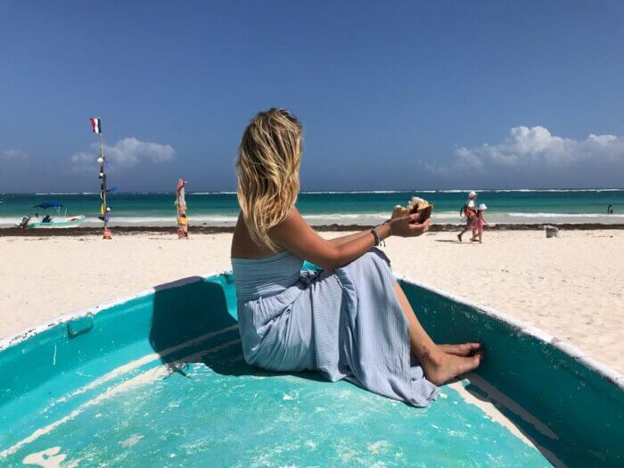 Žena sedící na modrém člunu na pláži Playa Paraíso v mexickém Tulum 