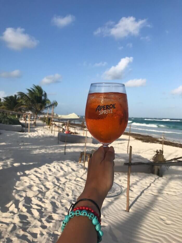 Ruka s koktejlem na pláži v Tulum v Mexiku